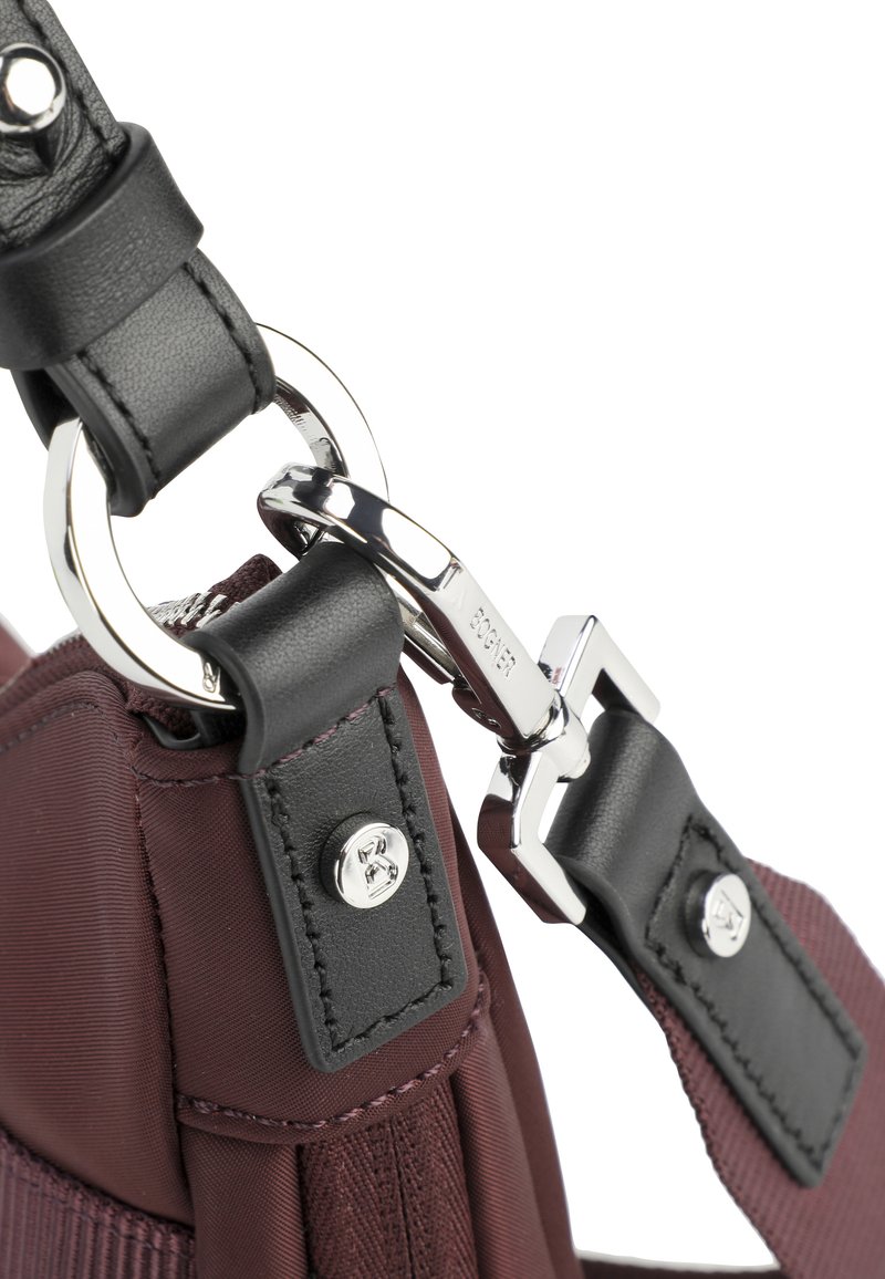 Burgunderfarbene Nylon-Tasche mit schwarzen Lederakzenten, ausgestattet mit einem Metallclip und silbernem Beschlag. Enthält genähte Details und einen strukturierten Trageriemen.