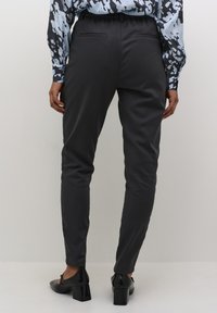 Charcoal gray tailored pants with a slim fit, elastic waist, and back pockets. Paired with a patterned light blue blouse and black block-heeled shoes.
