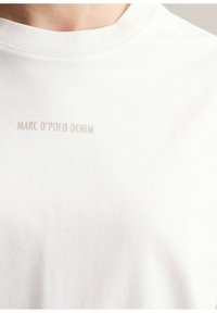 Weißes Baumwoll-T-Shirt mit Rundhalsausschnitt und kurzen Ärmeln, mit dezentem grauem Text "MARC O’POLO DENIM" auf der Brust.