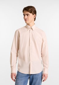  Lichtroze overhemd van katoen met een puntige kraag, lange mouwen en een wit logo op de borst. Gekocht met een blauwe jeans.