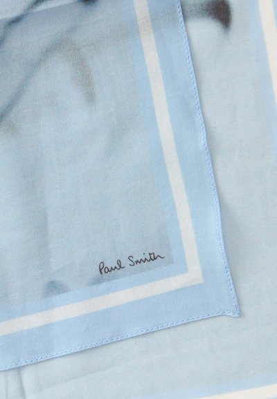 Tissu bleu clair avec des bords bordés de blanc et la signature "Paul Smith" imprimée près d'un coin.