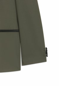 Khaki-Blazer mit glatter Textur, schwarzem Akzentband an der Taille und Knopfdetails an den Ärmeln, maßgeschneiderter Schnitt.