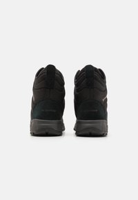Czarne wodoodporne buty z teksturowanej tkaniny, wyściełanym kołnierzem i wzmocnionym piętą. Posiadają gumową podeszwę zapewniającą trakcję i trwałość.