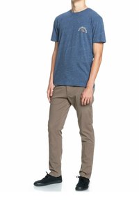 Marinblå t-shirt med kort ärm och grafik på bröstet, kombinerad med beige byxor och svarta sneakers. Strukturerad tyg.