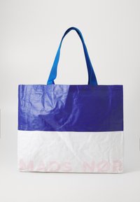 Blå og hvit totebag laget av slitesterkt, blankt materiale; har dristige horisontale fargeblokker og en trykt logo i rosa.
