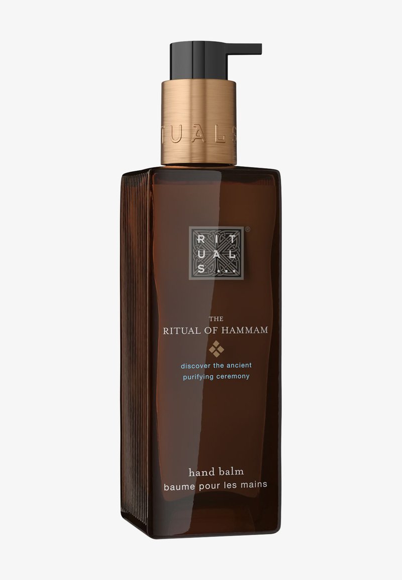 Donkerbruine rechthoekige pompflacon van Ritual of Hammam handbalsem met gouden dop en witte en blauwe tekst aan de voorkant.