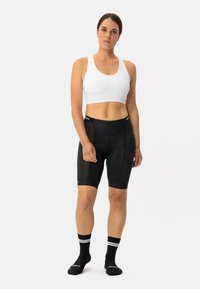 Shorts da ciclismo neri con pannelli in rete, abbinati a un reggiseno sportivo bianco. Il modello indossa calzini neri con righe bianche.