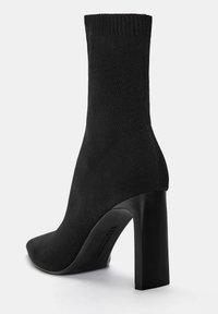 Stivaletto nero realizzato in tessuto lavorato a maglia, con punta appuntita e tacco a blocco. Texture liscia con parte superiore a coste.