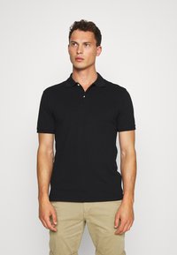 Polo negro de algodón, con cuello, mangas cortas y dos botones en el cuello. Textura suave con un corte clásico.