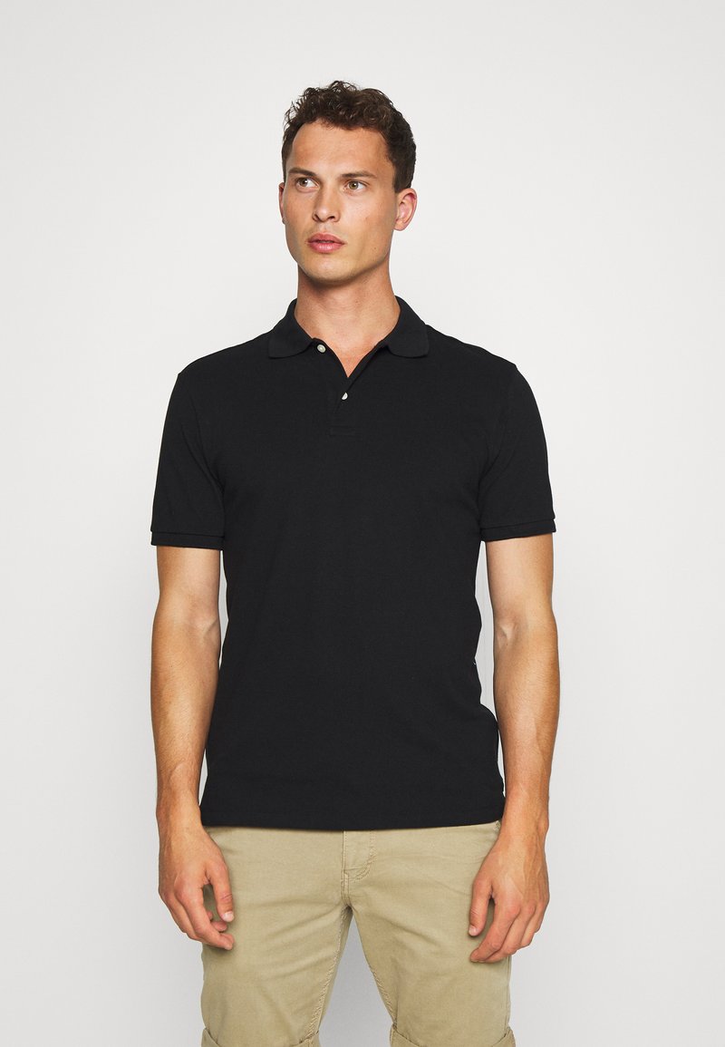 Polo negro de algodón, con cuello, mangas cortas y dos botones en el cuello. Textura suave con un corte clásico.