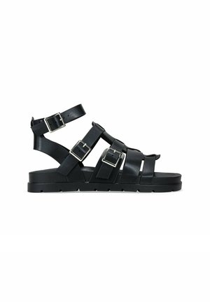 Sandalias de cuero negro con múltiples correas ajustables y hebillas plateadas, suela plana y un diseño texturizado para mayor tracción.