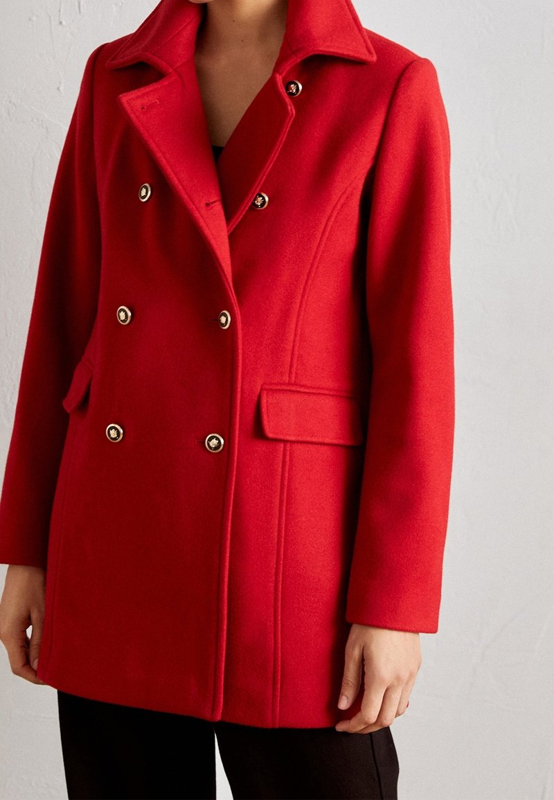 Manteau en mélange de laine rouge avec un design à double boutonnage, des accents de boutons dorés, un col cranté et des poches latérales. Texture douce et coupe ajustée.
