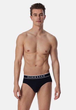 Schwarze Herrenunterwäsche mit einem weißen Logo-Bund, aus weichem Stoff gefertigt, mit einem taillierten Design und einer glatten Textur.