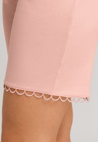 Rosa bomullsshorts med en slät textur, med en scallop-detalj i en ljusare rosa nyans. Designen är enkel och åtsittande.