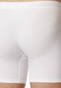 Boxer-briefs en coton blanc avec une texture lisse, dotés d'une coupe ajustée, d'une taille élastique et de coutures plates pour plus de confort.