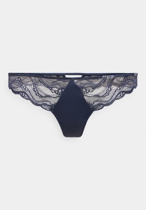 Strings en lace marine avec bords festonnés, dotées d'un panneau avant uni et de détails en dentelle complexe à l'arrière. Texture douce, design délicat.