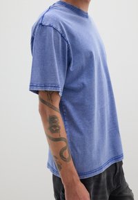 Blauw katoenen t-shirt met korte mouwen, ronde halslijn en contrasterende stiksels. Heeft een ontspannen pasvorm en een subtiele textuur.