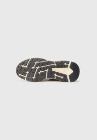 Semelle de chaussure en caoutchouc noir avec des semelles profondes, des motifs texturés et un intercalaire blanc. Le talon est arrondi avec un accent noir lisse.
