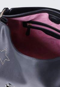 Borsa in pelle nera con un design a stelle, foderata in tessuto rosa e dotata di una tasca interna con zip per riporre gli oggetti.