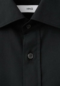 Czarna koszula zapinana na guziki z klasycznym kołnierzem. Wykonana z gładkiego materiału, posiada zapięcie na guziki z przodu oraz metkę widoczną wewnątrz kołnierza.