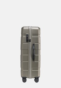 Kufr s tvrdým povrchem v olivově zelené barvě, vybavený strukturovaným povrchem, černým držadlem, kombinovaným zámkem a čtyřmi černými koly pro snadnou manipulaci.