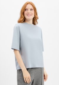 Lichtblauw T-shirt met korte mouwen en een hoge hals. Gemaakt van zacht materiaal, heeft het een losse pasvorm en een schone, minimalistische uitstraling.