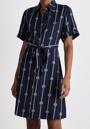 Vestido camiseros azul marino de manga corta con rayas verticales blancas, patrones de nudos circulares, botones frontales y cinturón de tela atado a la cintura.
