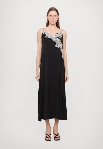Vestido negro con un diseño de encaje en el lado izquierdo, tirantes finos, una silueta fluida y una tela texturada.