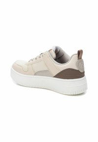 Zapatilla con suela blanca gruesa, parte superior de piel beige y paneles de acento en gris, punta redondeada y una lengüeta trasera marrón con detalle de logo en relieve.