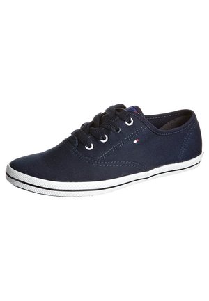 Marineblå lavtop canvas sneaker med sorte snørebånd, hvid gummisål og lille rød, hvid og blå flaglogo på siden.