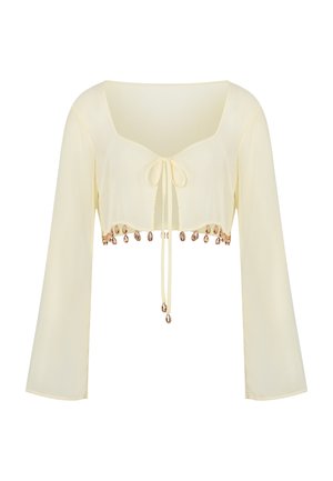 Cream long-sleeve cropped blouse with front tie and decorative gold shell charms along the hem.