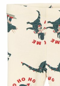 Krém színű pamut leggings dínó mintával sötétzöld színben, Mikulás sapkát viselő figurákkal, piros és szürke kiegészítőkkel.