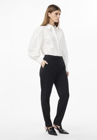 White button-up shirt with puff sleeves, paired with black tailored trousers and black pointed-toe heels. Minimalistic design, smooth texture.