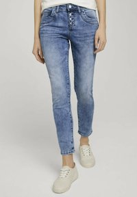 Ljust blå, slim-fit jeans med en urtvättad look. Har femfickorsdesign, knappgylf och subtila sömnadsdetaljer. Kombination med vita sneakers.