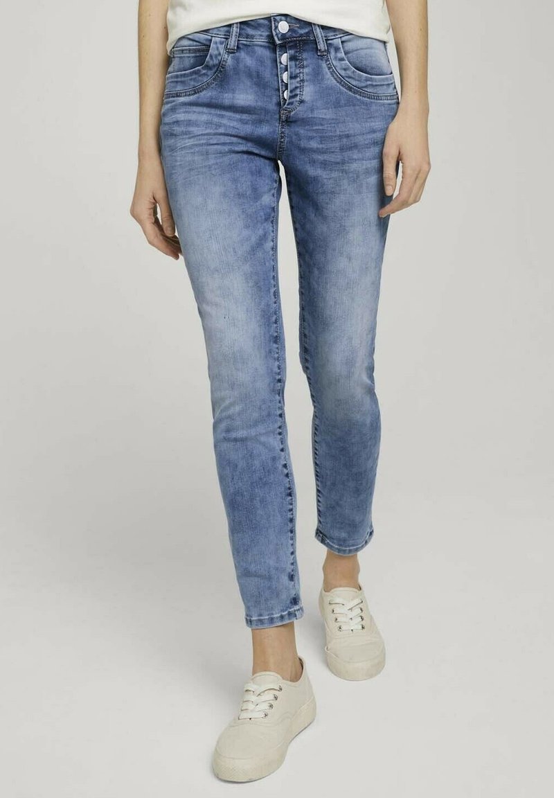 Ljust blå, slim-fit jeans med en urtvättad look. Har femfickorsdesign, knappgylf och subtila sömnadsdetaljer. Kombination med vita sneakers.