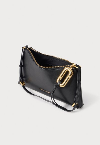 Μαύρο δερμάτινο βραχιολάκι Marc Jacobs με χρυσό φερμουάρ, χρυσό λογότυπο-για το κολιέ και αποσπώμενο λουρί σε απλό ανοιχτό φόντο.