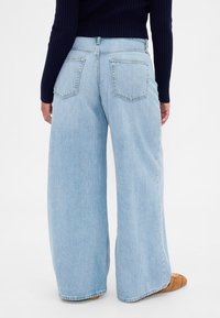 Svetlo modre kavbojke s širokimi hlačnicami in visokim pasom z vidnimi šivi. Imajo dva zadnja žepa in sproščen kroj, izdelane iz jeansa.