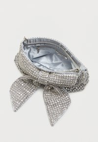 Srebrna kopertówka pokryta cyrkoniami, z tkaninowym detalem w kształcie kokardy, satynowym wnętrzem i kieszonką na zamek do przechowywania.