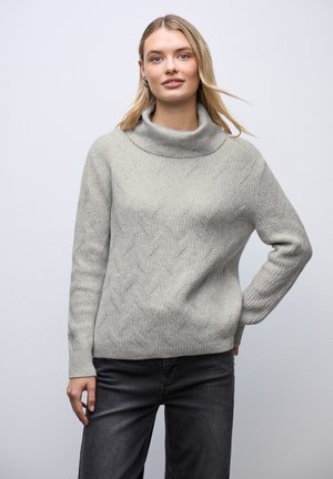 Grauer Strickpullover mit hohem Schalkragen, der ein strukturiertes Rautenmuster, gerippte Bündchen und eine lockere Passform aufweist. Kombiniert mit dunklen Jeans.