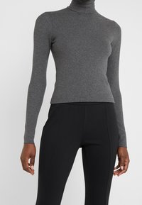 Grå polokrage med långa ärmar, tillverkad av ett mjukt, ribbat tyg. Den figurnära designen passar bra ihop med svarta leggings för en elegant look.