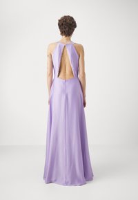 Šviesiai violetinė vakarinė suknelė su aukštu kaklu, atvira nugaros dalimi ir perlų formos akcentais. Plaukiantis audinys su lygiu paviršiumi ir elegantiška siluetu.