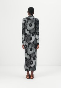 Long-sleeve, black dress with large gray floral pattern. Soft fabric, slim fit, mid-calf length, and high neckline. Simple sandals.