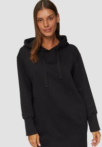 Zwarte hoodie jurk gemaakt van zacht materiaal met een comfortabele pasvorm, trekkoordkap en lange mouwen. Eenvoudig, effen ontwerp zonder patronen.
