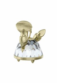 Figura in cristallo con base trasparente sfaccettata e parte superiore placcata in oro che richiama elementi marini, tra cui una conchiglia e due pinne stilizzate.