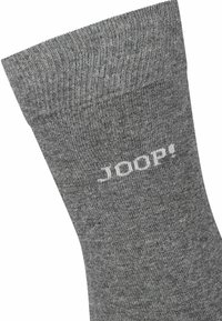 Calzino grigio con una texture a coste, caratterizzato da un logo bianco alla caviglia. Progettato per comfort e vestibilità. Nessun motivo o hardware presente.