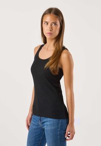 Zwarte ribgebreide tanktop met een ronde hals en brede bandjes, gecombineerd met blauwe jeans. Gladde textuur, aansluitend ontwerp.