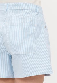 Shorts à rayures bleu clair et blanches en mélange de coton avec une coupe droite, dotés de deux poches arrières et de coutures visibles.