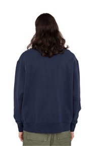 Felpa blu navy a collo rotondo con polsini e orlo a coste. Il tessuto sembra morbido, con una vestibilità rilassata e senza grafiche o motivi visibili.