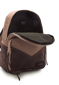 Brauner Rucksack aus zwei Materialien mit glattem oberen Teil und strukturiertem unteren Abschnitt, ausgestattet mit einem Reißverschluss und einem Logo-Patch.