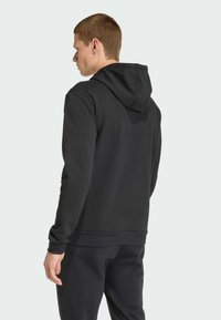 Sweatshirt à capuche noir avec une texture douce, des poignets côtelés et un ourlet droit. Conçu avec une coupe décontractée et un style minimaliste.